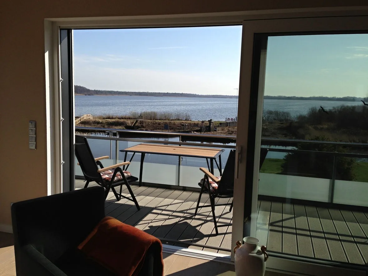Blick aus einer Ferienwohnung über den Balkon mit Tisch und Stühlen auf den Bederkesaer See